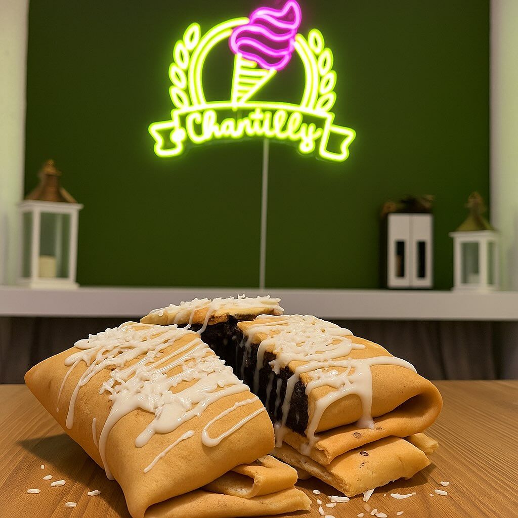 L'insegna luminosa di Chantilly all'interno del locale, con i dolci in primo piano